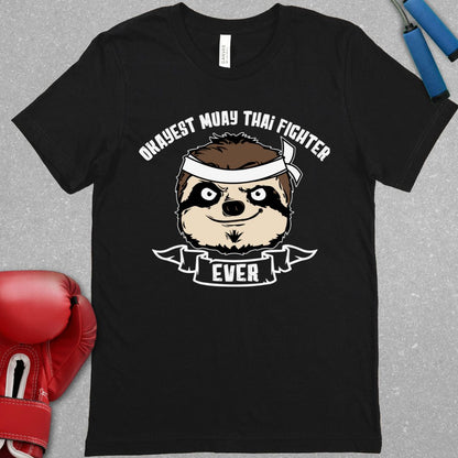 Black shirt with text that says Okayest Muay Thai Fighter ever and there is  picture of a racoon’s face wearing a bandana