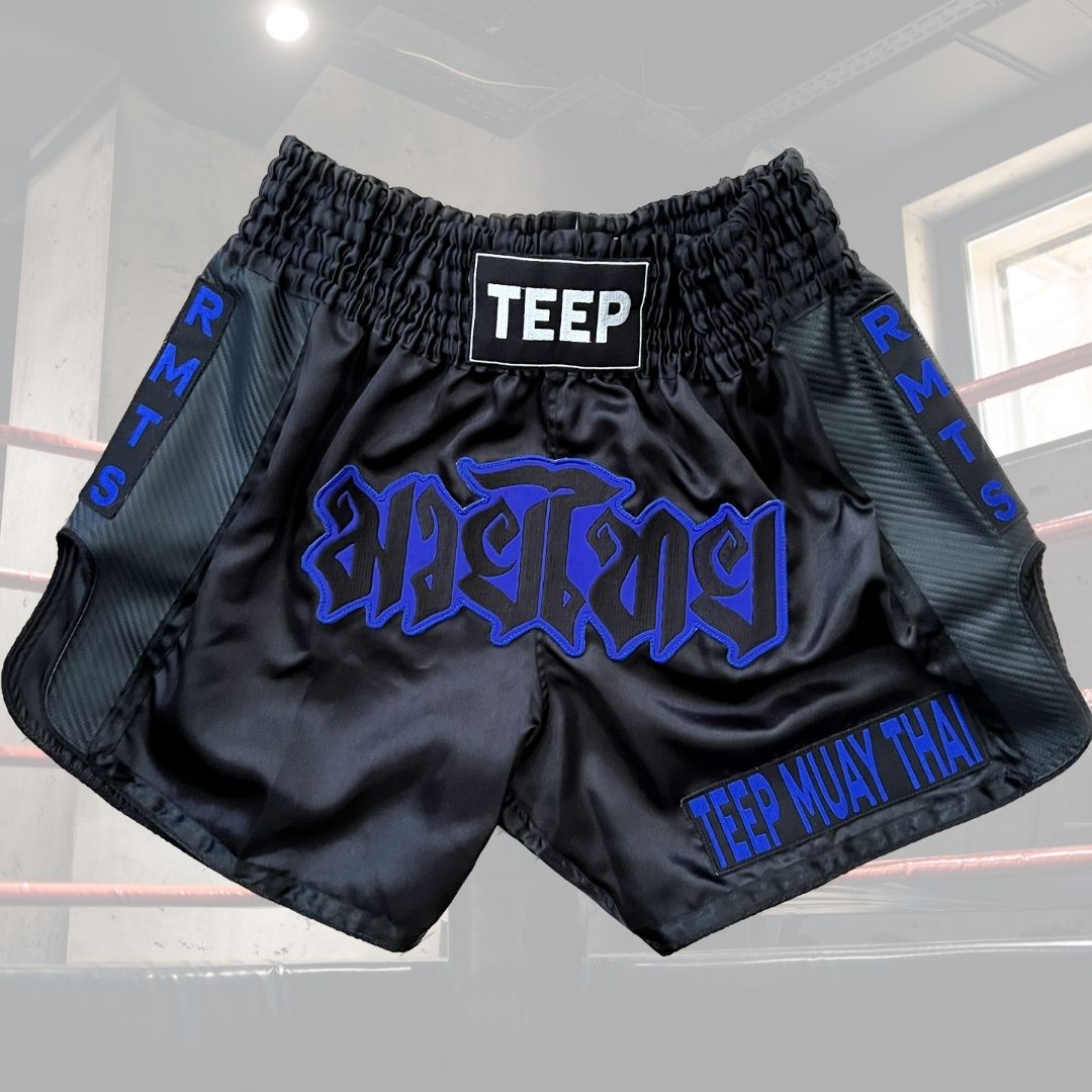 Muay Thai shorts with Teep stitched on the waist band. Muay Thai in Thai writing is stitched on the front of the shorts as well as the words Teep Muay Thai on the bottom left corner. The abbreviation RMTS which stands for Random Muay Thai Syndrome is stitched on both side panels of the shorts and runs down.