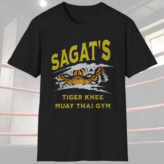 Black shirt with a design that says Sagat’s Tiger Knee Muay Thai gym and there is a picture of a tiger’s eyes