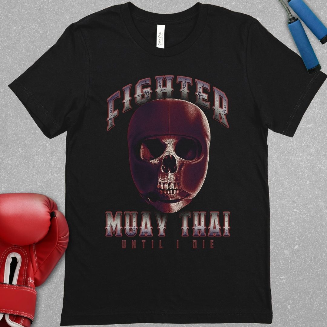 Black shirt with the word Fighter at the top and Muay Thai Until I die at the bottom. In between those words there is a picture of a skull in protective head gear.