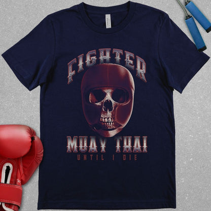 Navy shirt with the word Fighter at the top and Muay Thai Until I die at the bottom. In between those words there is a picture of a skull in protective head gear.